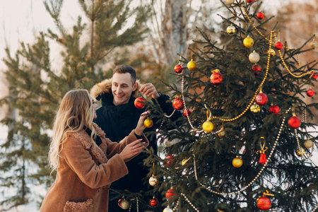 Young adult couple decorates christmas tree in winter forest. New year pine holiday party celebration conceptの写真素材