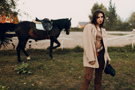 Cowgirl in brown clothes with her horse at outdoors ranchの写真素材