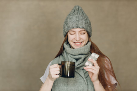 Young woman has flu catarrh ill sick disease treatment cold hold packaging of tablets pillow drugs and glass of waterの写真素材