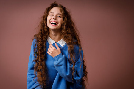 Happy laughing young adult woman wearing winter blue sweater indoors looking at camera with joyful smileの写真素材