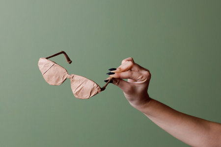 Female hand holds a brand new glasses wrapped in rustic beige craft paper. Black Friday shopping concept.の写真素材