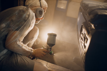 Car painter in protective clothes and respirator mask painting vehicleの写真素材