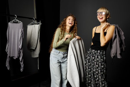 Beautiful smiling young woman fashion stylist designer helping choose clothes to customer client at fashion boutiqueの写真素材