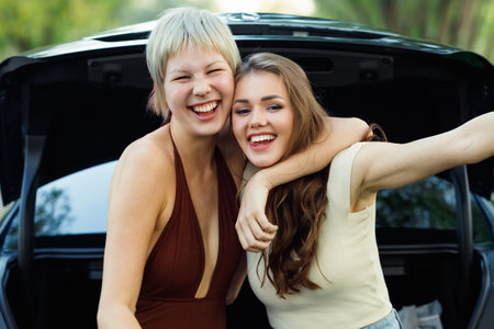 Two woman drivers at car smiling. Cute young happy female driving car vehicleの写真素材