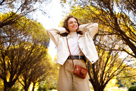 Smiling young woman with the photo camera walking in the forest