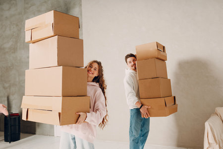 Happy young family couple man and woman carry cardboard boxes to new real estate apartment. Moving and delivery concept.の写真素材