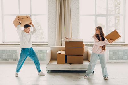 Happy young family couple man and woman plays and throws cardboard boxes on new home. Moving delivery concept.の写真素材