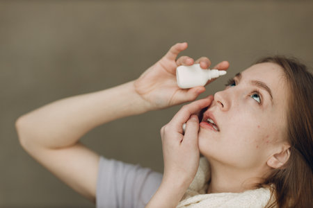 Young woman has flu catarrh ill sick disease treatment cold hold medicine eye sprayの写真素材