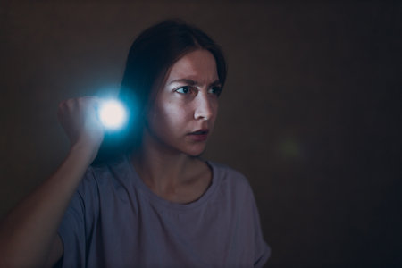 Woman scared holding hand flashlight in darkness and afraid of violence criminal robberyの写真素材
