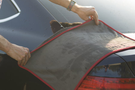 Worker washing car at car wash and wipes vehicle with ragの写真素材