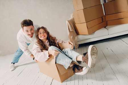 Happy young family couple man haul move woman inside box. Moving with cardboard boxes to new home apartment conceptの写真素材