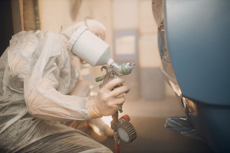 Car painter in protective clothes and respirator mask painting vehicle carの写真素材