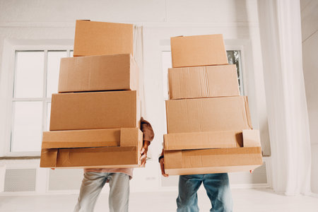Happy young family couple close up man and woman moving with cardboard boxes to new estate home apartment.の写真素材