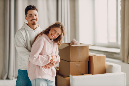 Happy young family couple hugging after moving cardboard boxes to their new apartment.の写真素材
