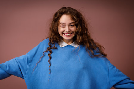 Happy young adult woman wearing spring blue sweater indoors looking at camera with joyful smileの写真素材