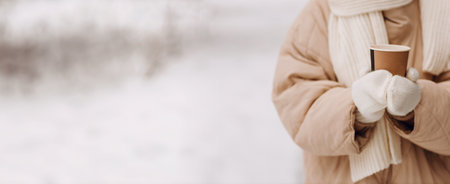 Female hands holding coffee hot drink cup and enjoys winter weather at snowy street copy spaceの写真素材