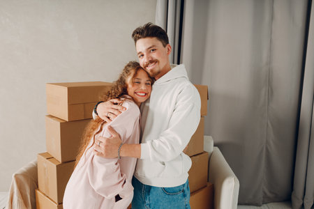 Happy young family couple man and woman hugging and moving with cardboard boxes to new estate home...