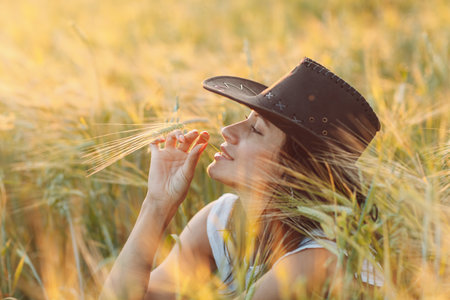 Woman farmer in cowboy hat at agricultural field on sunset.の写真素材