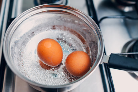 Saucepan stainless steel with boiling eggs breakfast in a water on a gas stove.