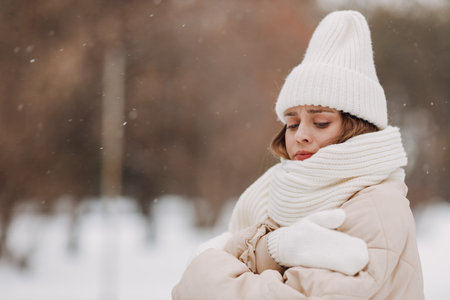 Young woman dressed coat scarf hat and mittens in winter weather at snowy winter parkの写真素材