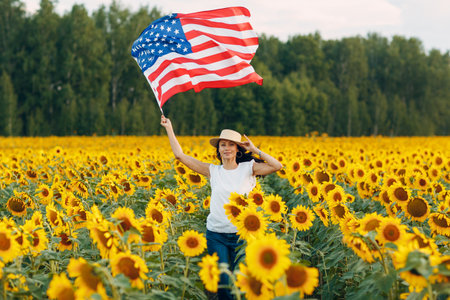 Young woman with American flag in the sunflower field. 4th of July Independence Day USA conceptの写真素材