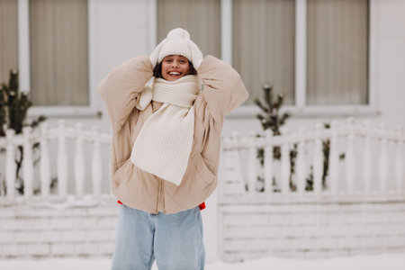 Happy smiling young woman portrait dressed coat scarf hat and mittens enjoys winter weather at snowy...