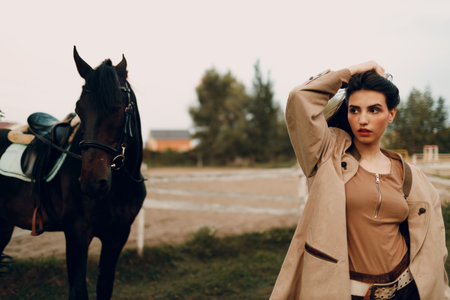 Cowgirl in brown clothes with her horse at outdoors ranchの写真素材
