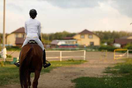 Woman rider in helmet and white uniform preparing horseの写真素材