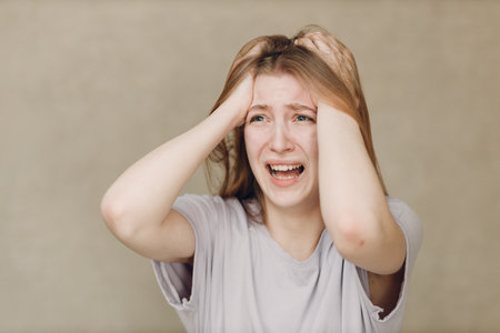 Portrait of young caucasian actress crying upset woman looking at camera against beige background. Acting test casting auditionの写真素材