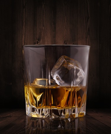 Glasses of whiskey with ice cubes on wood backgroundの写真素材