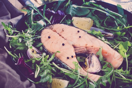Salmon steak with fresh vegetables in a pan on a wooden table wiの写真素材