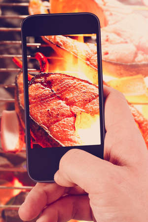 Using smartphones to take photos of grilled salmon steak and pepper with instagram style filterの写真素材