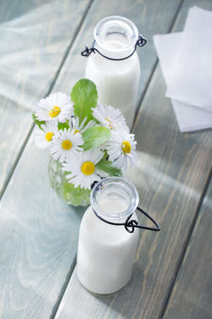 Milk and summer flowers on wood backgroundの写真素材