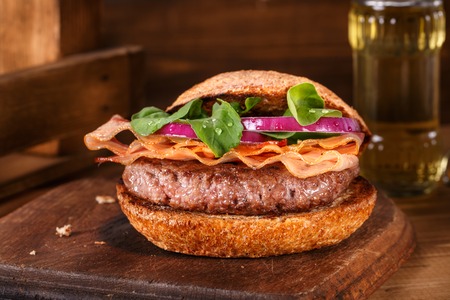 Burger with meat and vegetables close up on a cutting board on wooden backgroundの写真素材