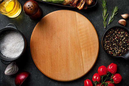 Wooden cutting board on table background with cooking ingredient and herbal spices. Top view, flat...