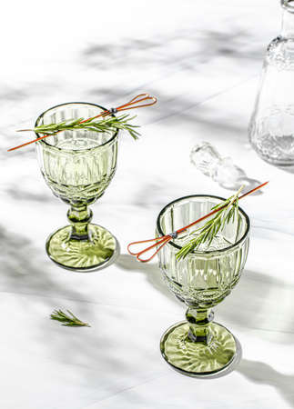 Green crystal wine glass over white background with leaves shadowの写真素材