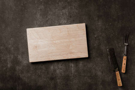 Old vintage kitchen utensils. Fork, knife, cutting board top view on stone table backgroundの写真素材