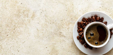 Fresh morning espresso over line concrete background. Coffee cup on saucer with scattered roasted...