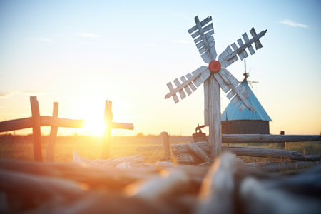 sun rising behind a rustic windmillの素材