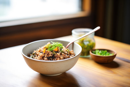 bowl of mixed quinoa with a spoon on a kitchen tableの素材