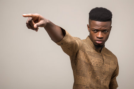 cropped studio shot of a young african man pointing forward against a grey backgroundの素材