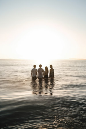 shot of a group of friends standing in the ocean togetherの素材