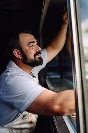 shot of a man opening the shutters at his food truckの素材