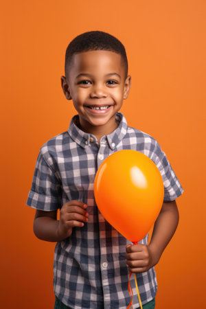 adorable young african american boy smiling at you while holding a balloon in his handの素材