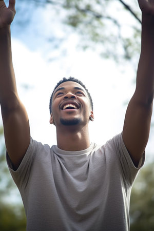 shot of a young man standing outdoors with his arms raisedの素材
