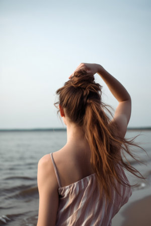 rearview shot of a woman holding her hair up by the sea with copyspaceの素材