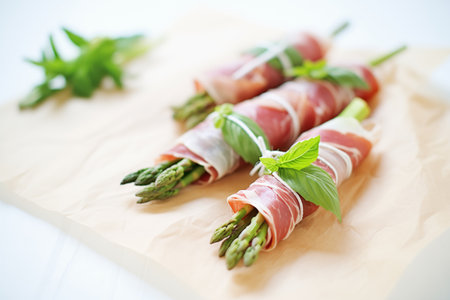 fresh asparagus wrapped in prosciutto, tied with chive strings, laid on parchment paperの素材