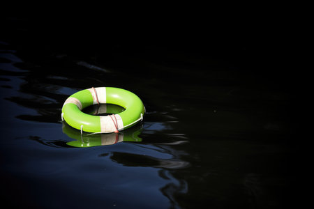 neon green life buoy on dark water for contrastの素材