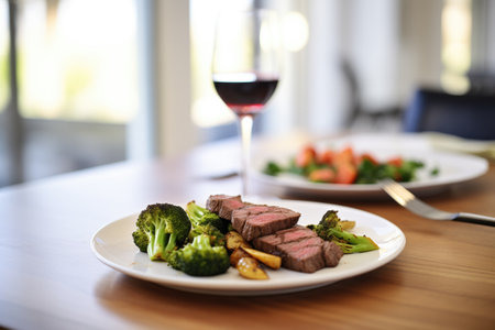 beef and broccoli with a glass of red wine on dining tableの素材