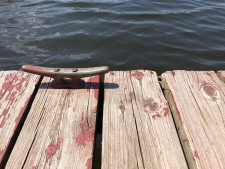 An old dock with chipped red paint sits on a murky lake.の写真素材